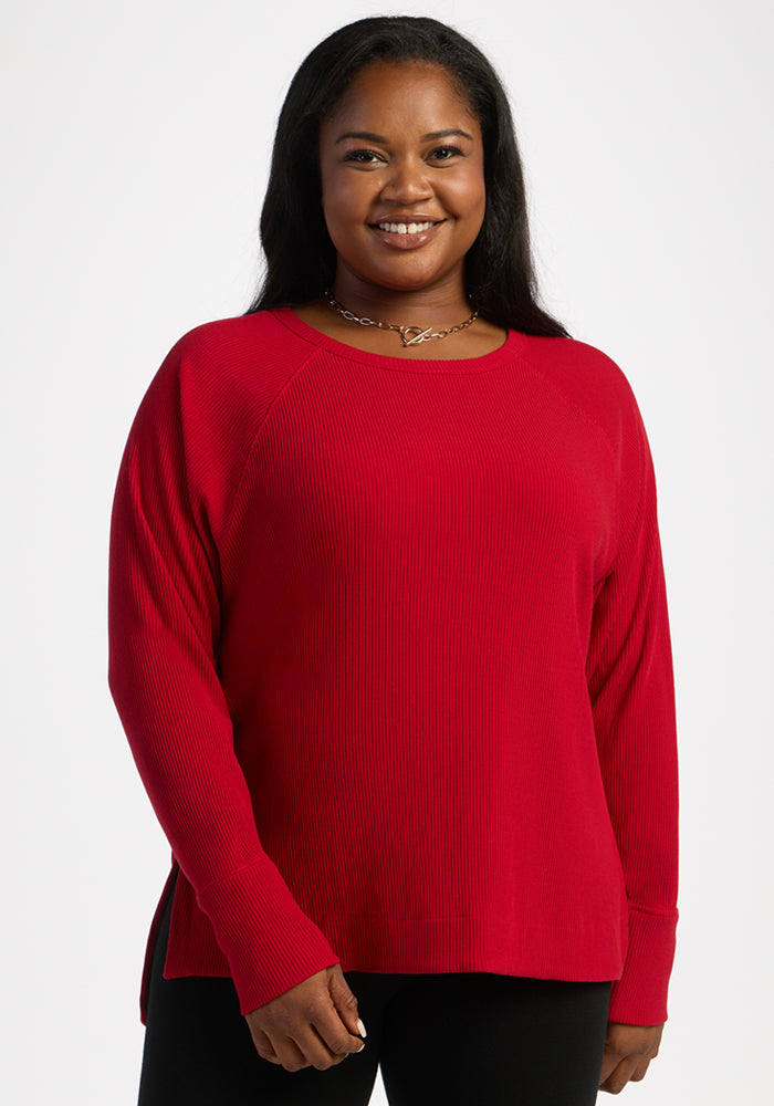 Woman smiling in the Woolx Ainsley Sweater - Maraschino Cherry, with a necklace, against a light background. 