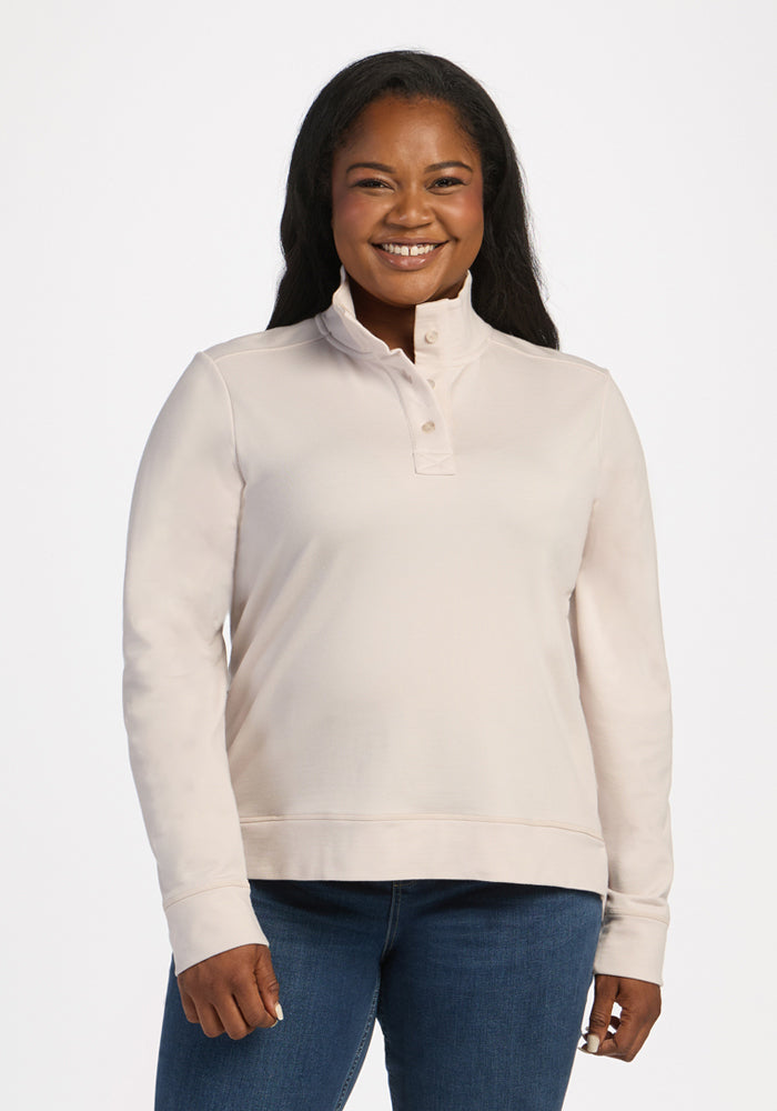 Woman smiling in the Woolx Annie 3 Button Pullover - Ecru and blue jeans, standing against a white background. 