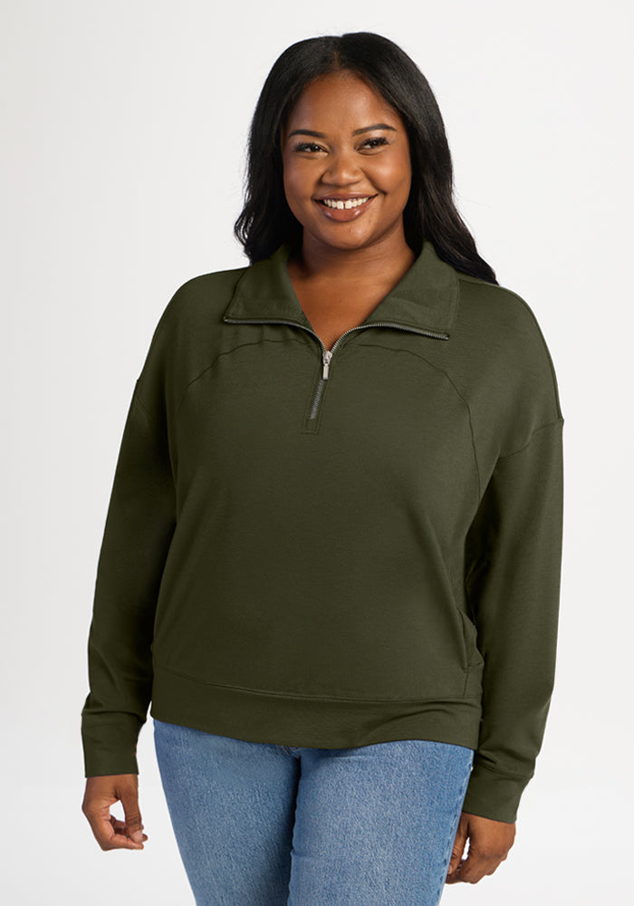 A smiling woman wears an olive green, lightweight merino Woolx Tori 1/4 Zip - Everleaf pullover. 