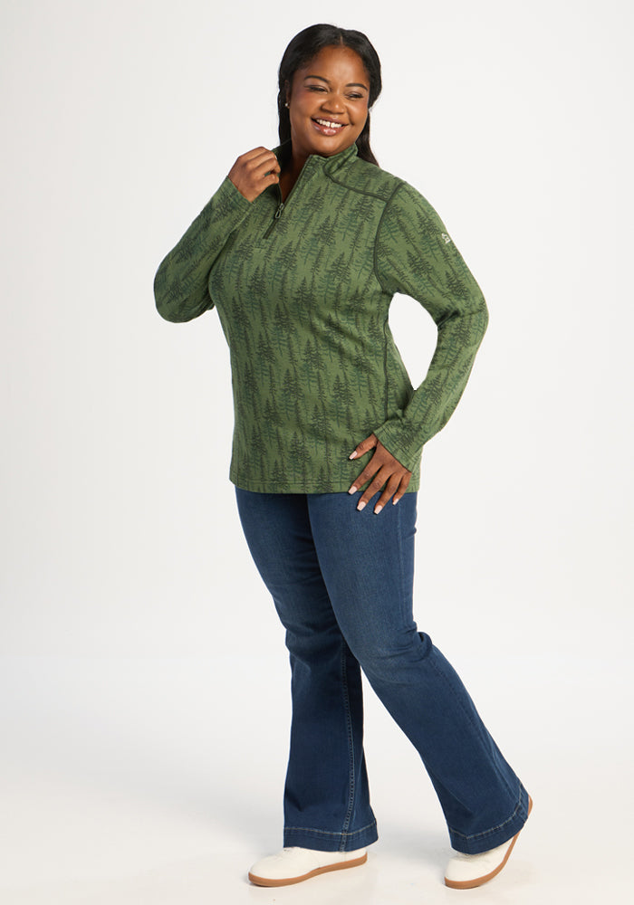 Woman wearing Woolx Emi 1/4 Zip - Forest Friends base layer and blue jeans, smiling against a white background.