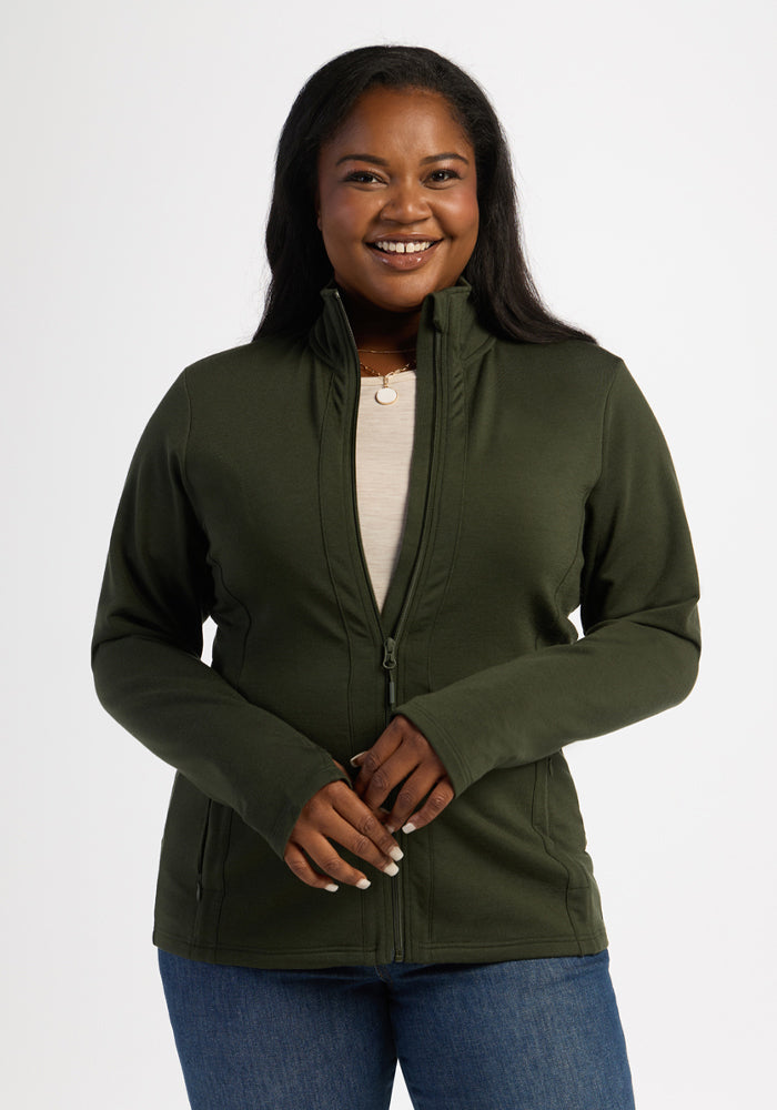 Smiling woman in Woolx Finley Zip Up Sweatshirt - Duffel Bag and jeans, standing against a plain white background. 