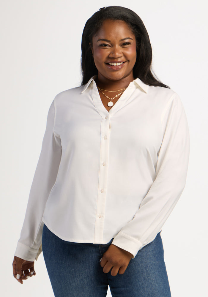 Smiling woman wearing the Woolx Lorelai Button Up in Eggshell and blue jeans against a plain white background. 