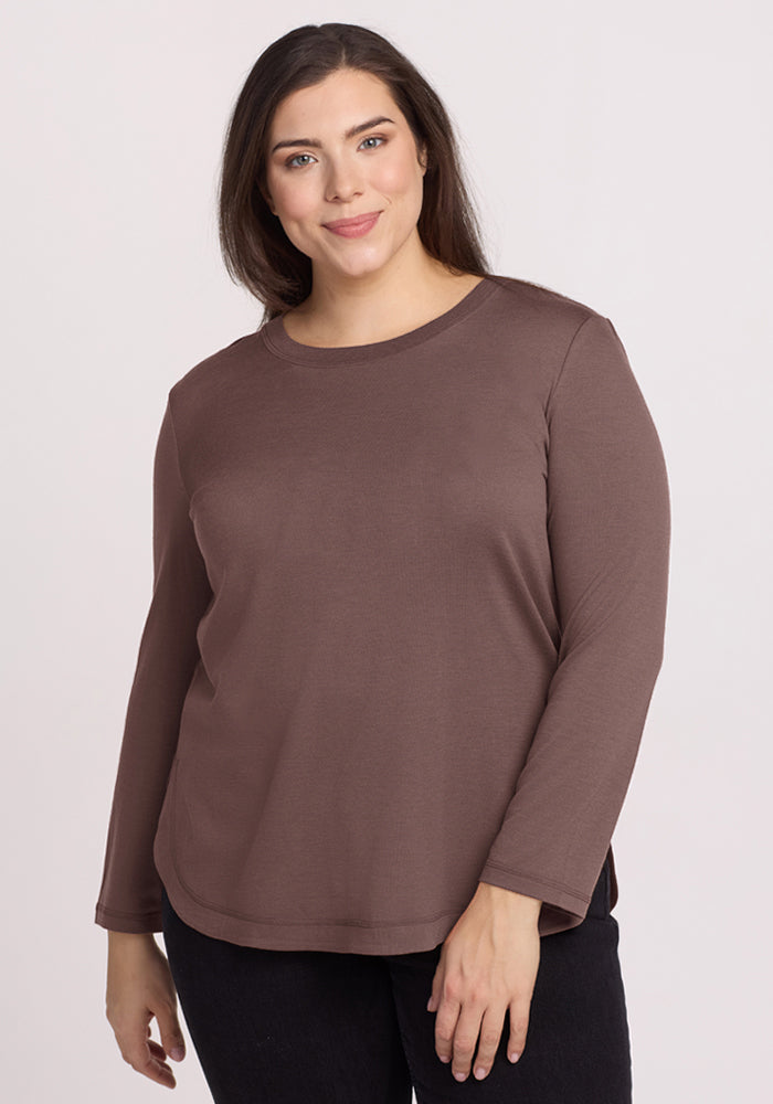 Woman in the Woolx Hazel Tunic in Peppercorn and black pants, smiling in front of a neutral background. 