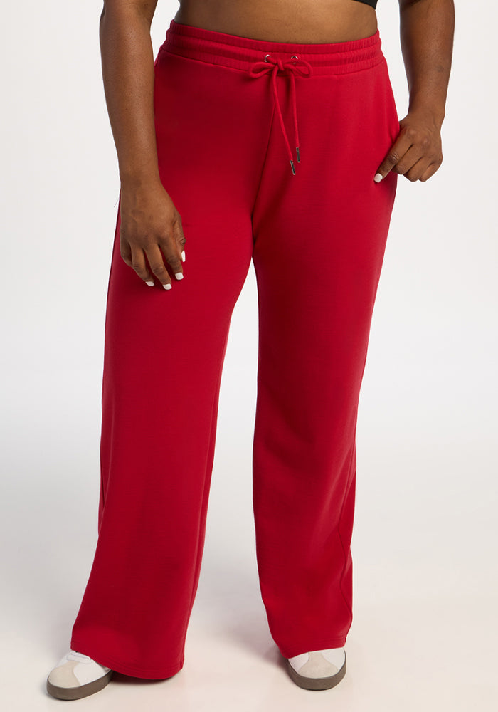 Model wears Woolx Eloise Wide Leg Pants in Maraschino Cherry with white shoes, standing against a white background. 