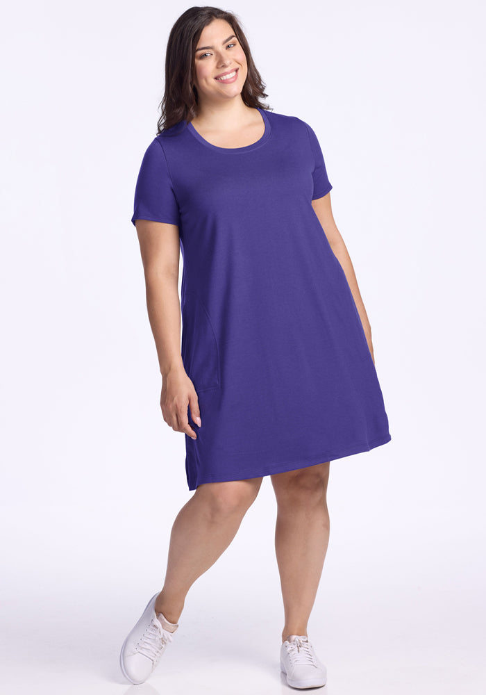 Woman in the Woolx Georgie Dress - Berry Indigo and white sneakers smiles against a white background. 