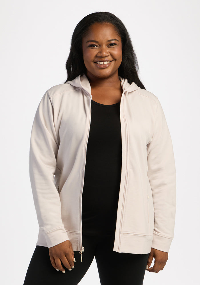 Woman smiling in Woolx Darby Zip Up Hoodie - Ecru over a black top, standing against a plain white background. 