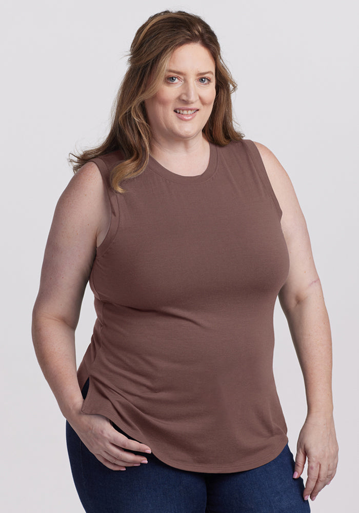 A woman in a Woolx Bella Tunic Top - Peppercorn and blue jeans smiles at the camera against a plain background. 
