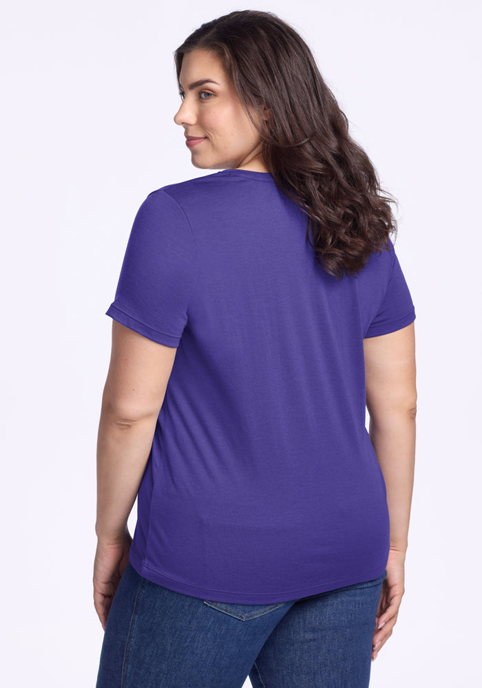 Woman with long brown hair in the Woolx Junie V Neck - Berry Indigo, standing and looking over her shoulder.