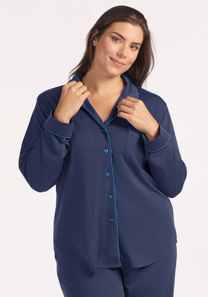 A woman wearing a navy blue Harper FeatherTouch® Pajama Set with bright blue piping.