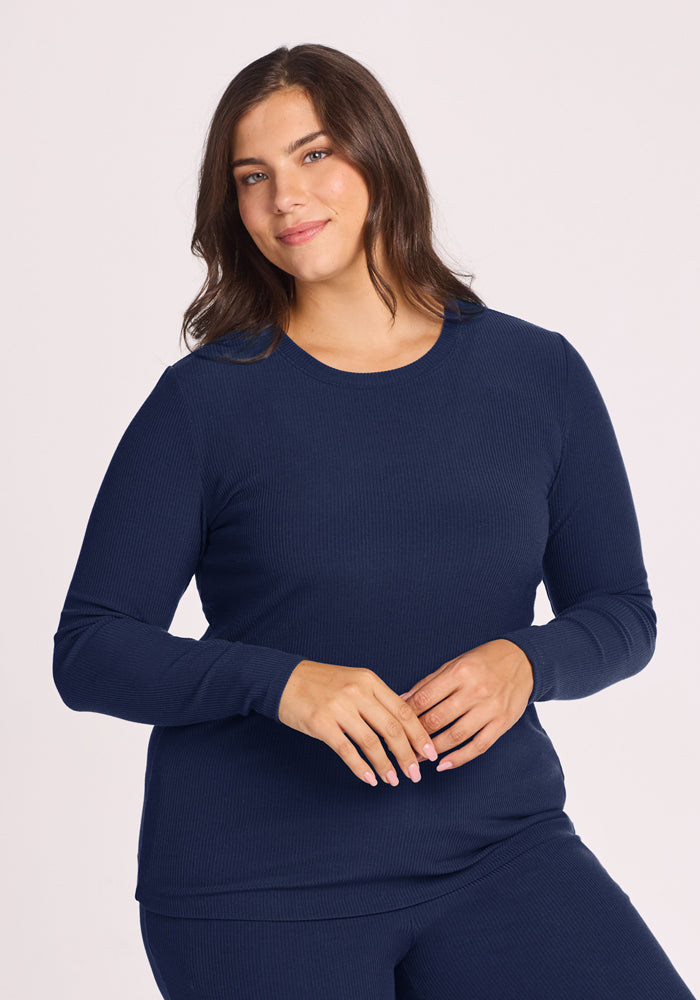 Woman in the Woolx Hadley Ribbed Crew - Ocean Cavern, smiling and standing against a light background. 