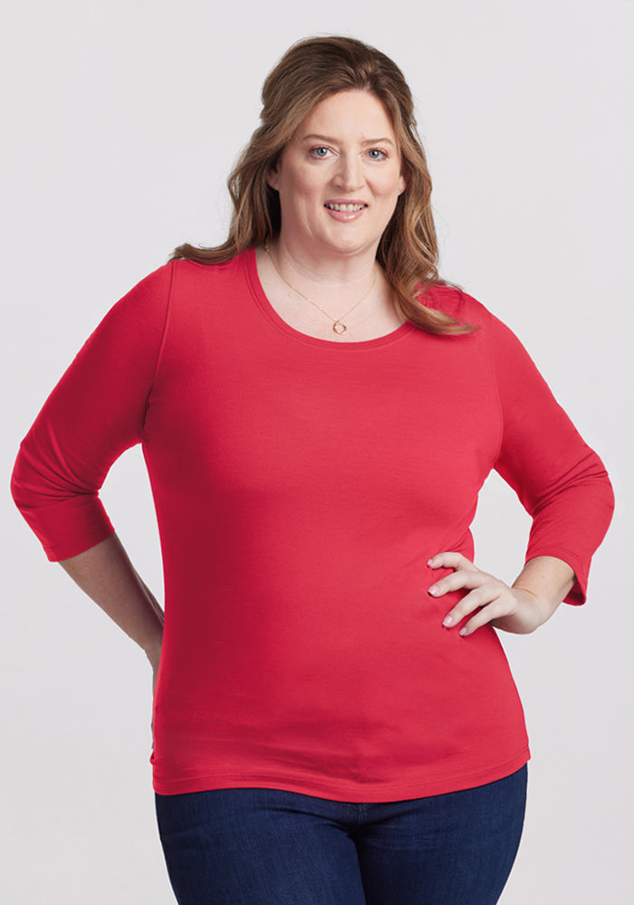 A woman smiles in the Woolx Jenny 3/4 Sleeve Crew Neck - Berry Ice Pop, with jeans against a plain background. 