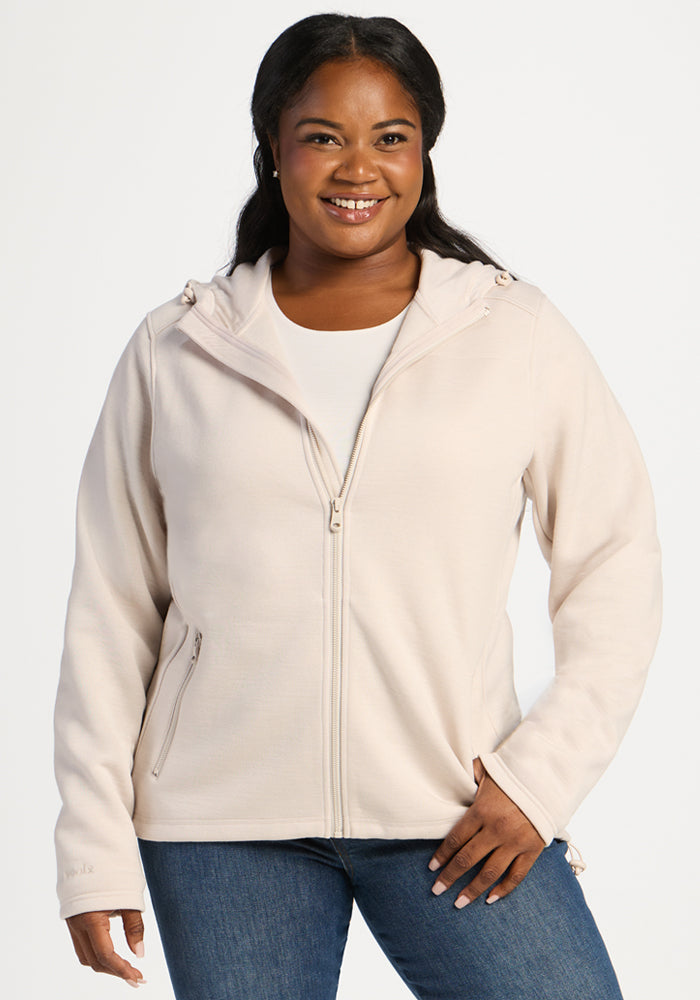 A smiling woman wearing an ecru Woolx Cubby Hooded Sweatshirt. 