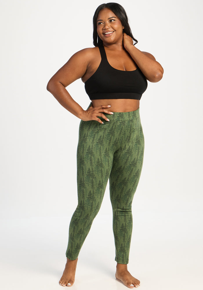 Woman in Woolx Taylor Baselayer Leggings - Forest Friends, barefoot and smiling, stands with one hand on her hip.