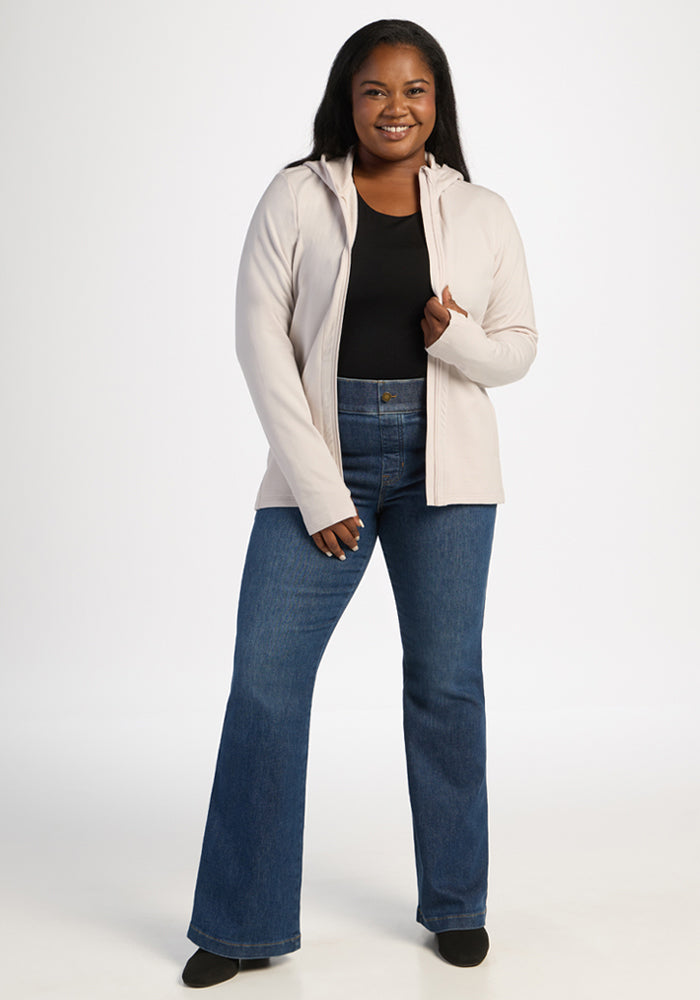 Woman in the Woolx Zoey Zip Up Hoodie - Ecru, black shirt, and jeans smiles, ready for cold weather.