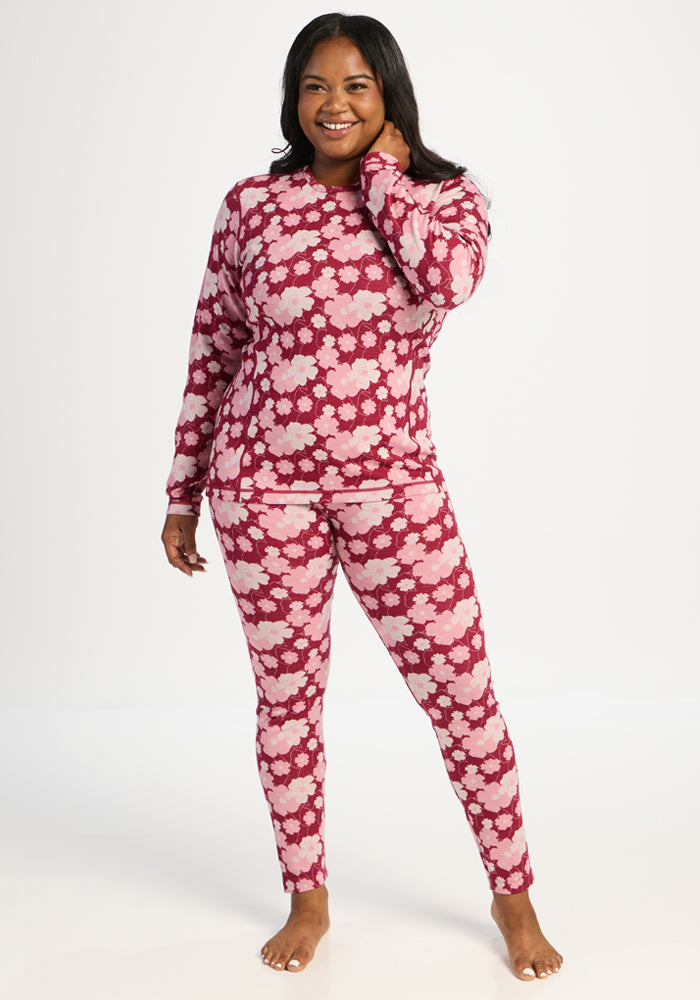 Woman smiling, barefoot, in Woolx Maddie Baselayer Top - Floral Crush, standing on a white background.