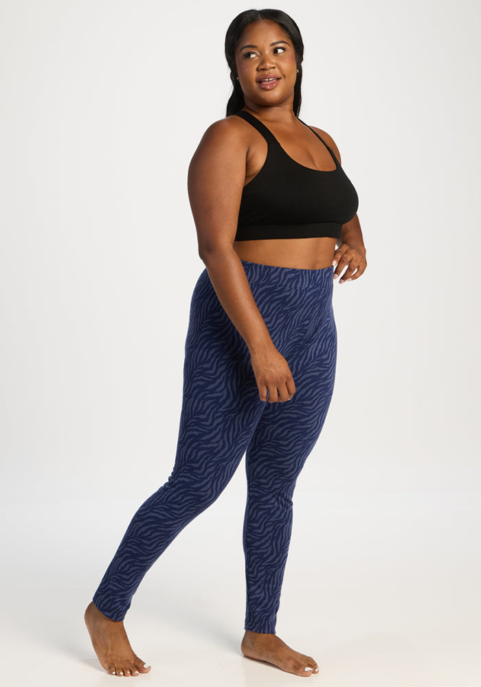 Woman in Woolx Taylor Baselayer Leggings - Midnight Safari, barefoot and smiling on a white background.