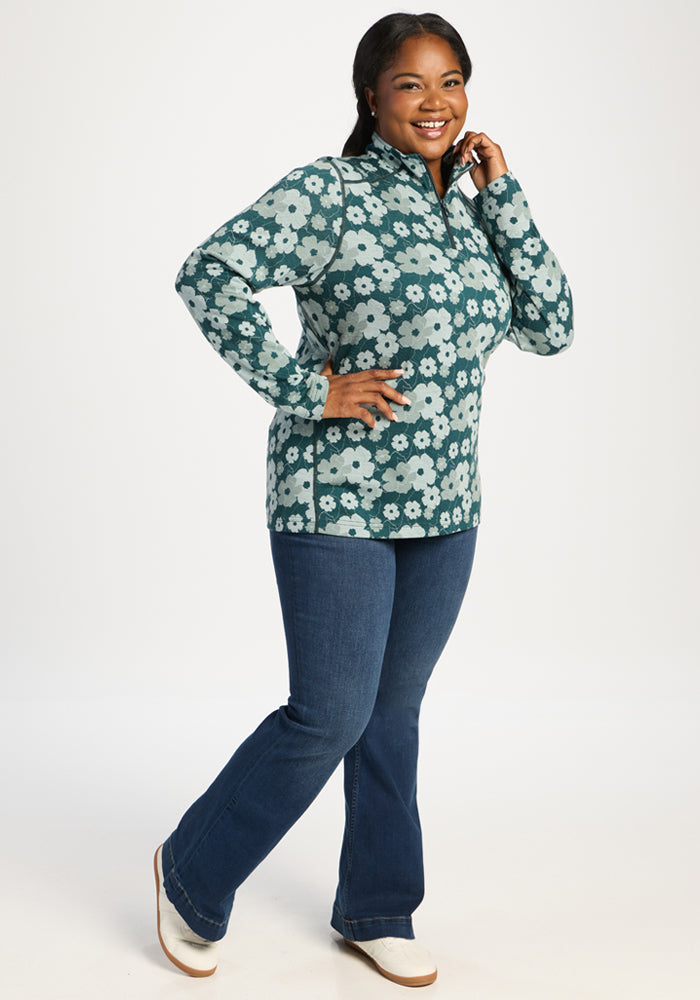 Woman wears Woolx Emi 1/4 Zip - Coastal Wildflower, smiling with one hand on her face and the other on her hip.
