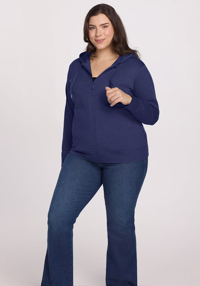 Woman in the Woolx Ryann Hoodie - Twilight Storm and jeans smiles at the camera, standing against a white background.
