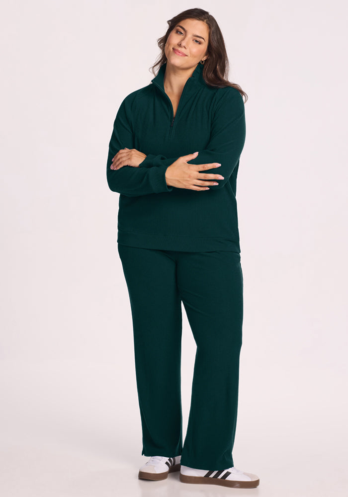Woman in the Woolx Quinn Ribbed 1/4 Zip - Deep Pine, arms crossed and smiling against a plain background.