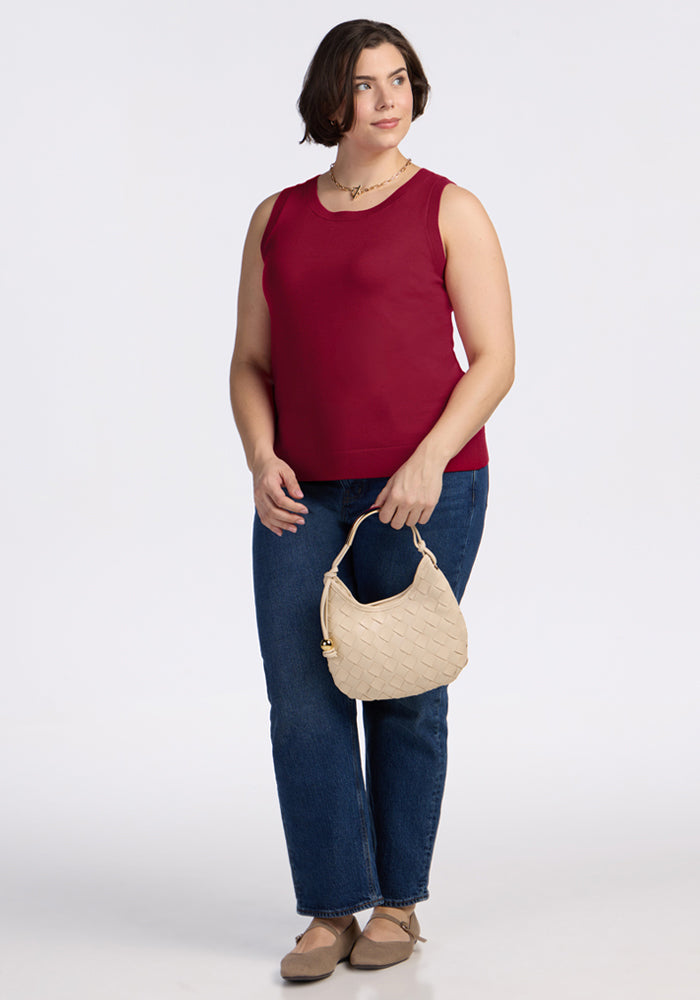 Woman in Woolx Chessy Tank Top - Beet Red, blue jeans, beige flats, holding a woven handbag and smiling.