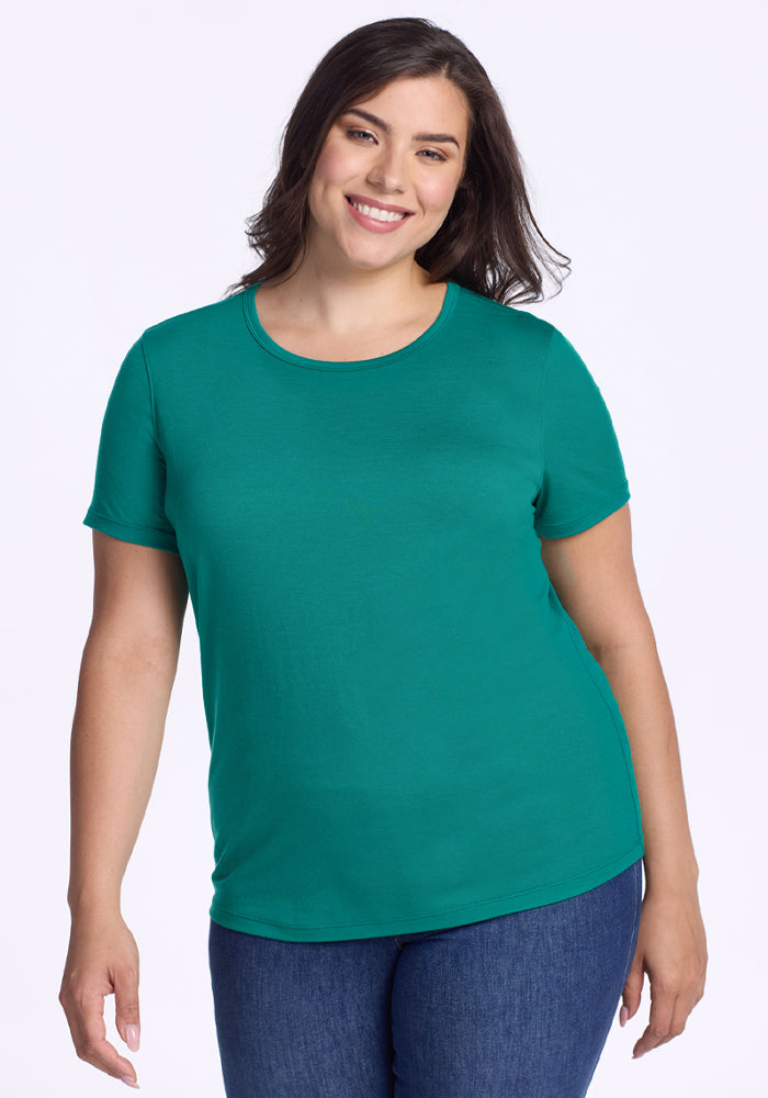 Woman in a Woolx Liza Crew Neck Tee - Cabana Crush and blue jeans smiles against a plain white background. 