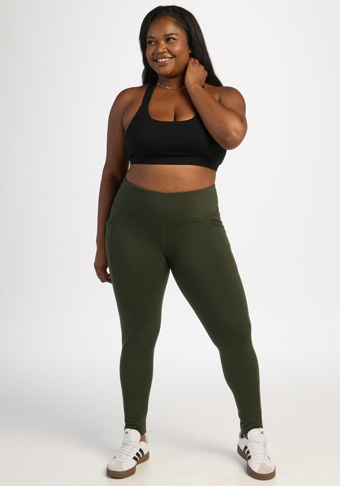 Woman in Woolx Frost Leggings - Duffel Bag and black sports bra smiles, hand playfully touching her hair.