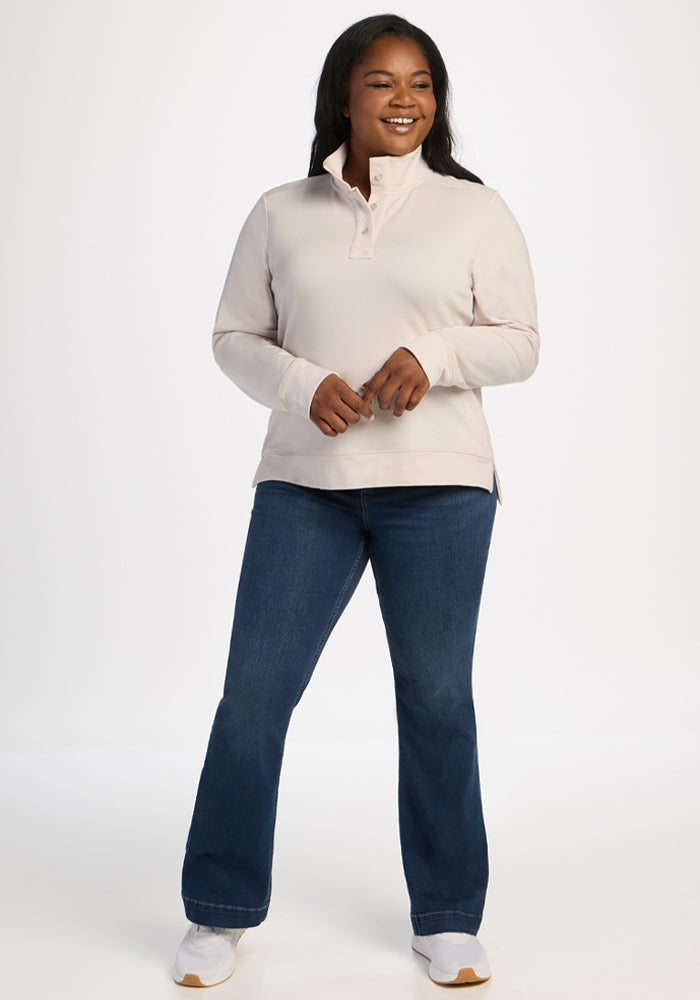 Woman smiles in Woolx Annie 3 Button Pullover - Ecru, blue jeans, white sneakers, on a white background.