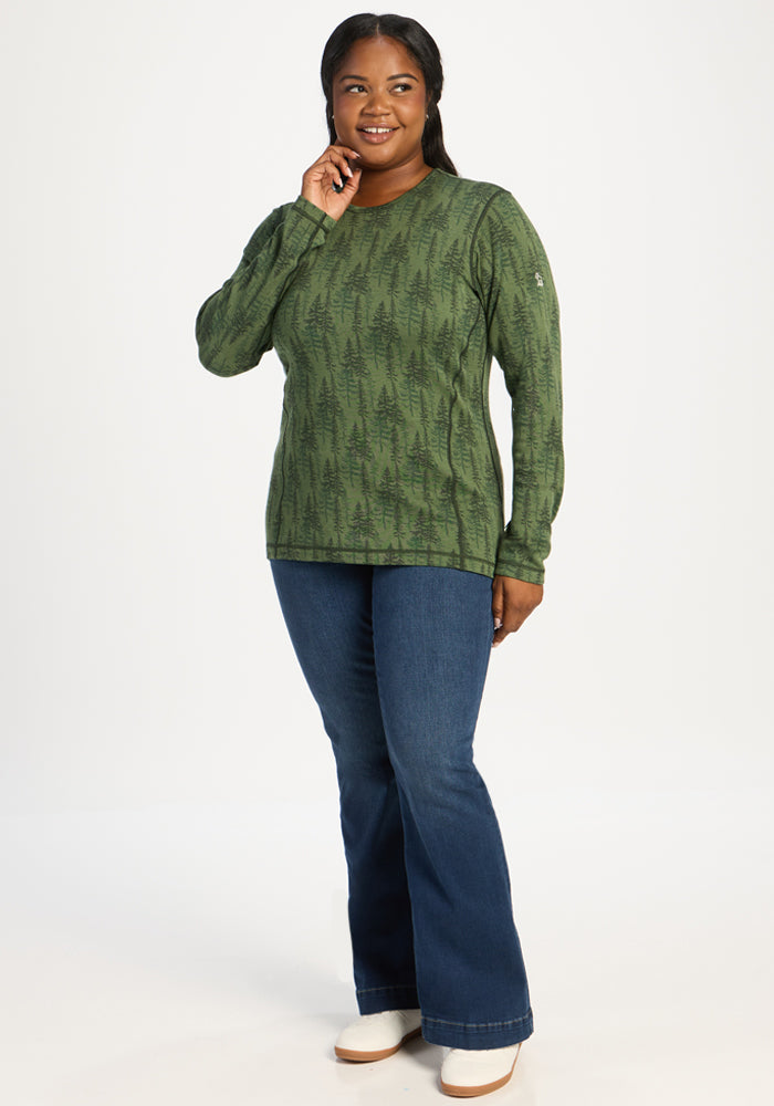 Smiling woman in Woolx Maddie Baselayer Top - Forest Friends and blue jeans poses on a white background.