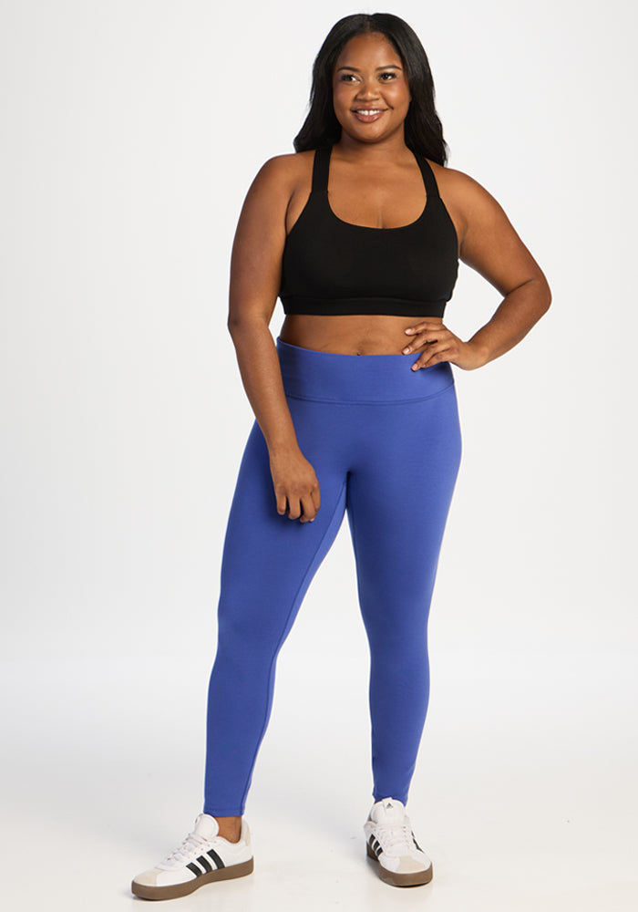 A woman wearing a black sports bra, royal blue Angela Leggings, and white sneakers.