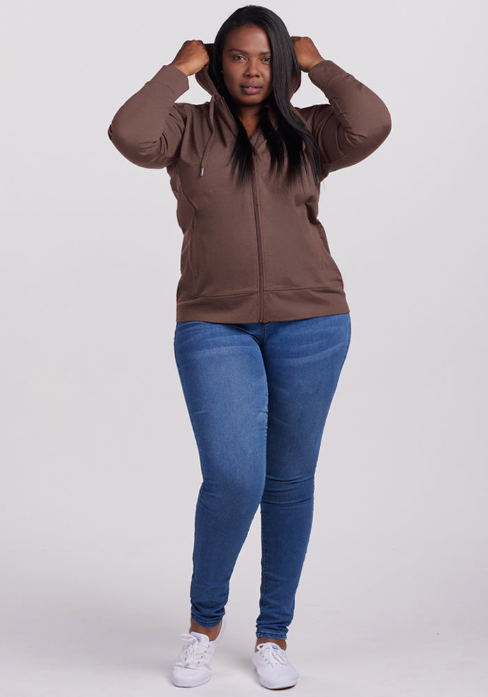 Woman in a Woolx Ryann Hoodie - Peppercorn adjusts the hood—a travel essential—against a plain background.