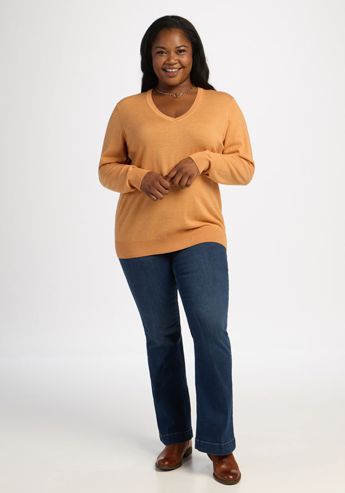 Woman in a Woolx Francesca Sweater - Butterscotch and blue jeans smiles against a plain white background.