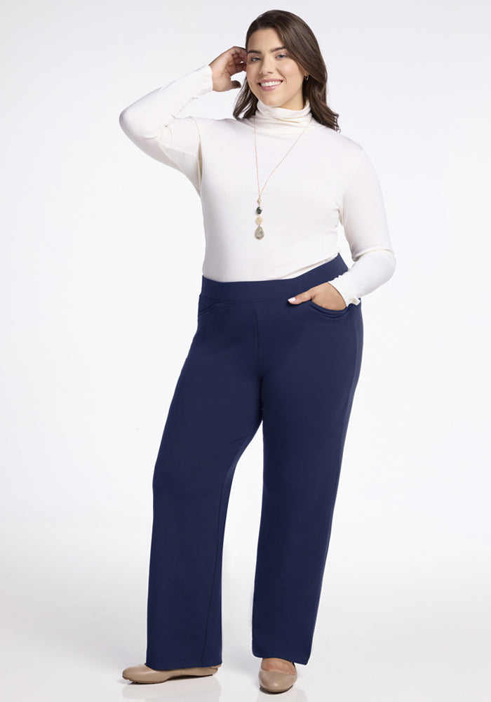 Woman in Woolx Ellie Wide Leg Pants - Ocean Cavern smiles, one hand in pocket, the other touching her hair.