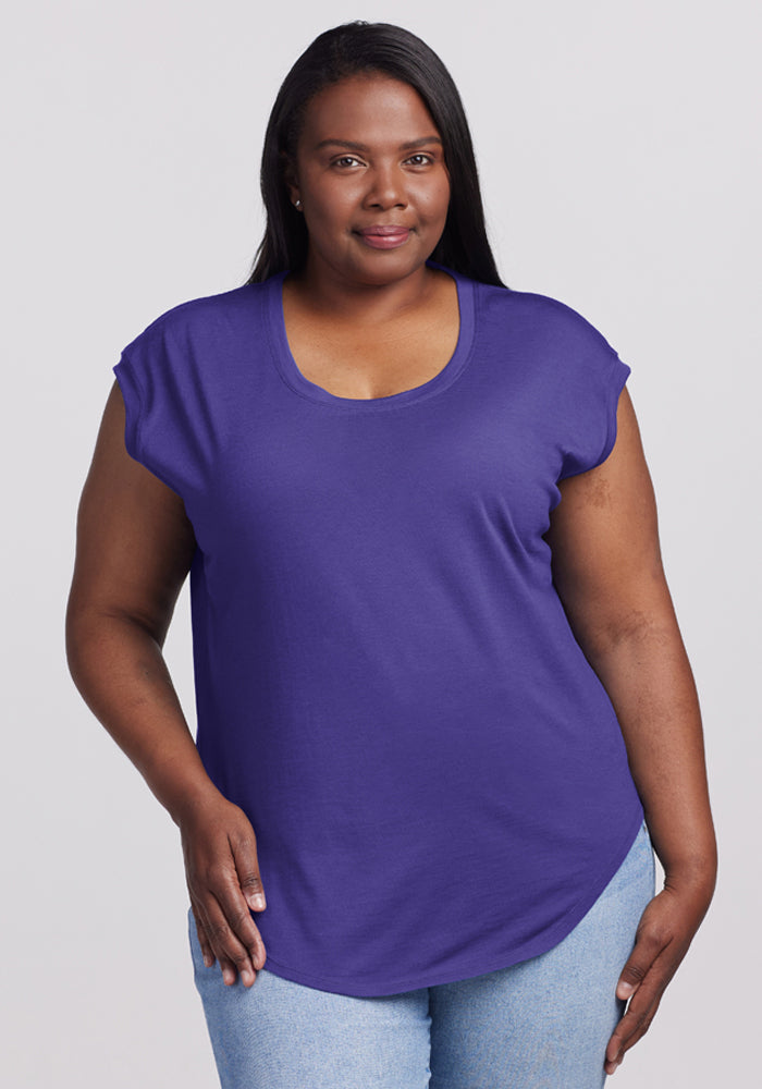 A woman wears the Woolx Gabi Tunic Top in Berry Indigo with light blue jeans, facing the camera and smiling slightly. 