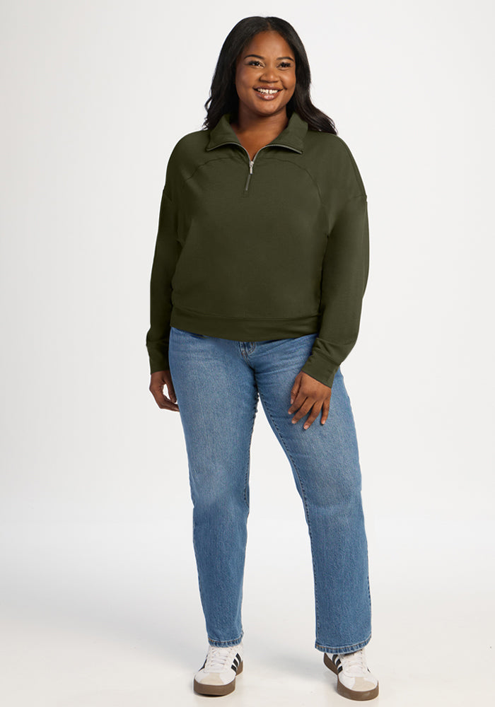 A woman wearing an Everleaf Tori 1/4 Zip, blue jeans, and sneakers.