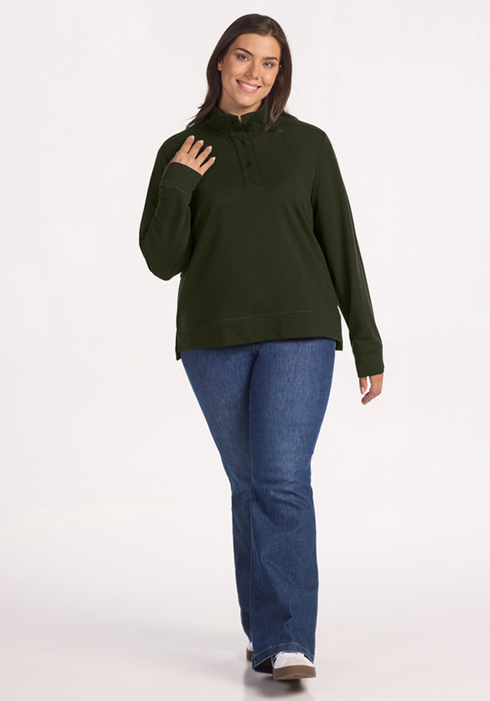 Woman smiles in Woolx Annie 3 Button Pullover - Duffel Bag, blue jeans, and white shoes on a light background.