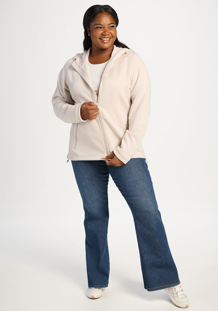 A person wearing a cream Cubby Hooded Sweatshirt - Ecru over a white shirt and blue jeans.