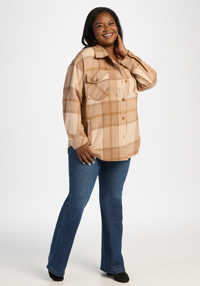 Woman smiling in Woolx Sawyer Shacket - Saddleback Plaid and blue jeans, standing against a plain white background.