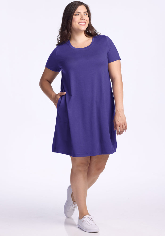 Woman in the Woolx Georgie Dress - Berry Indigo with pockets and white sneakers stands against a white background.