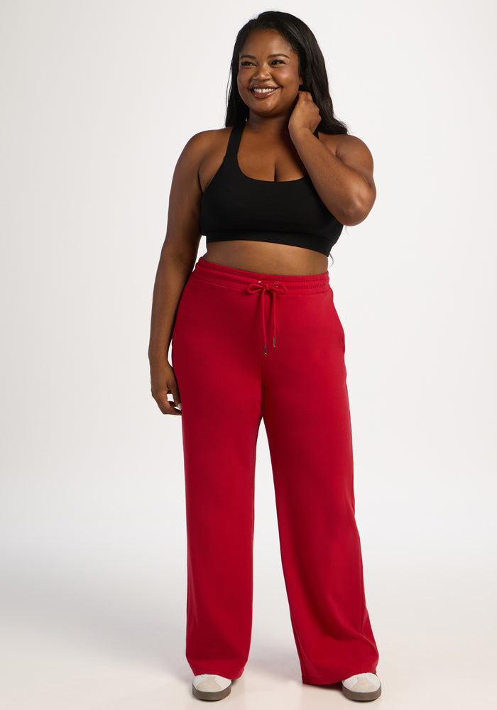 Woman smiles in a black crop top and Woolx Eloise Wide Leg Pants - Maraschino Cherry, against a white background.