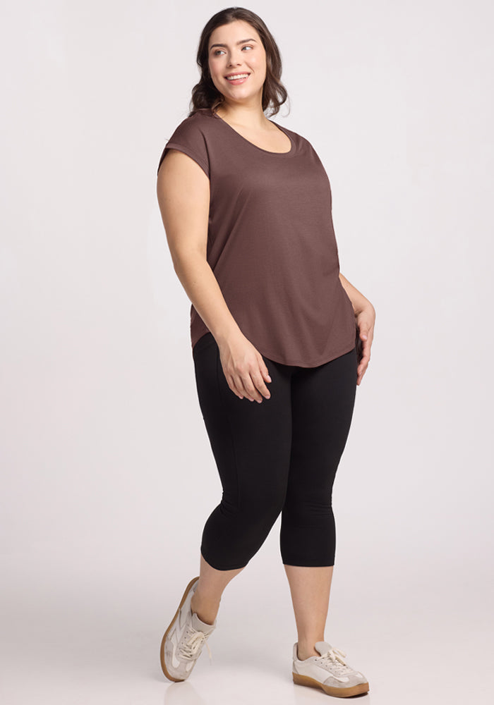 Woman smiling in the Woolx Gabi Tunic Top in Peppercorn, black leggings, and white sneakers against a plain background.