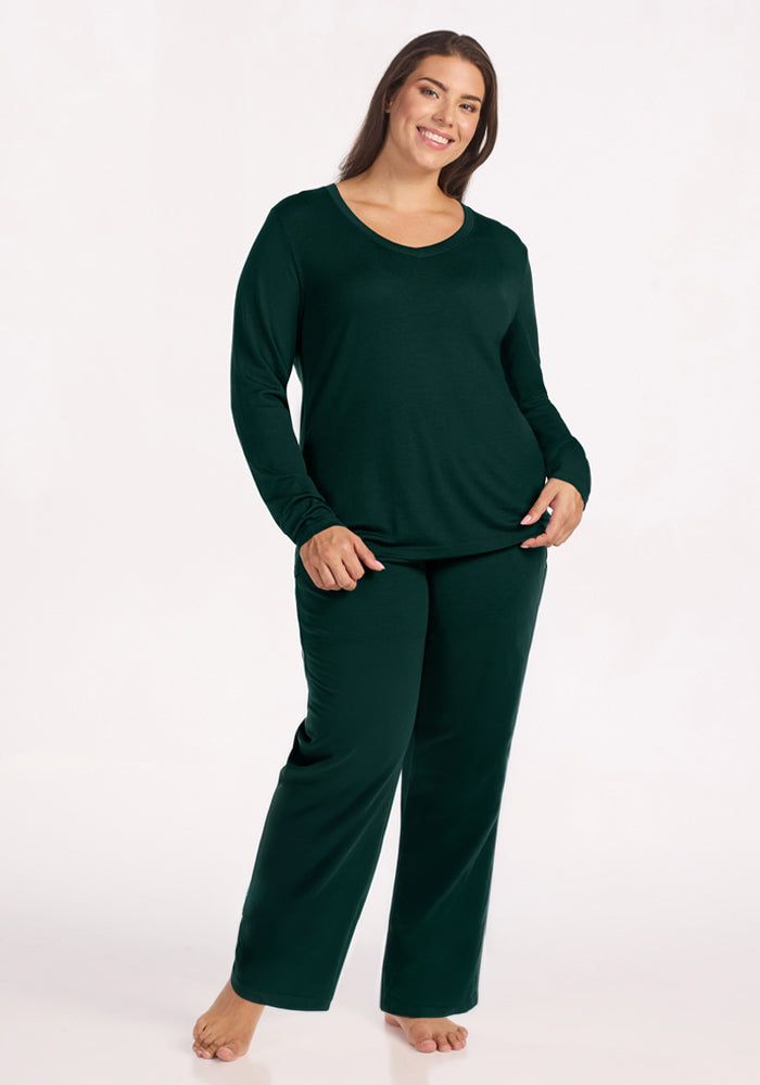 A smiling woman wearing a deep pine Lily V Neck Lounge Top and matching lounge pants.