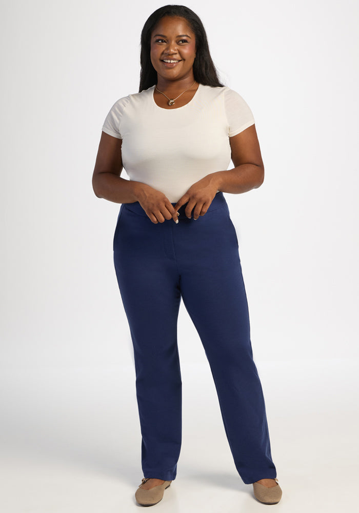 Woman smiling in a white tee, Woolx Emerson Straight Leg Pants - Ocean Cavern, beige shoes, on white background.