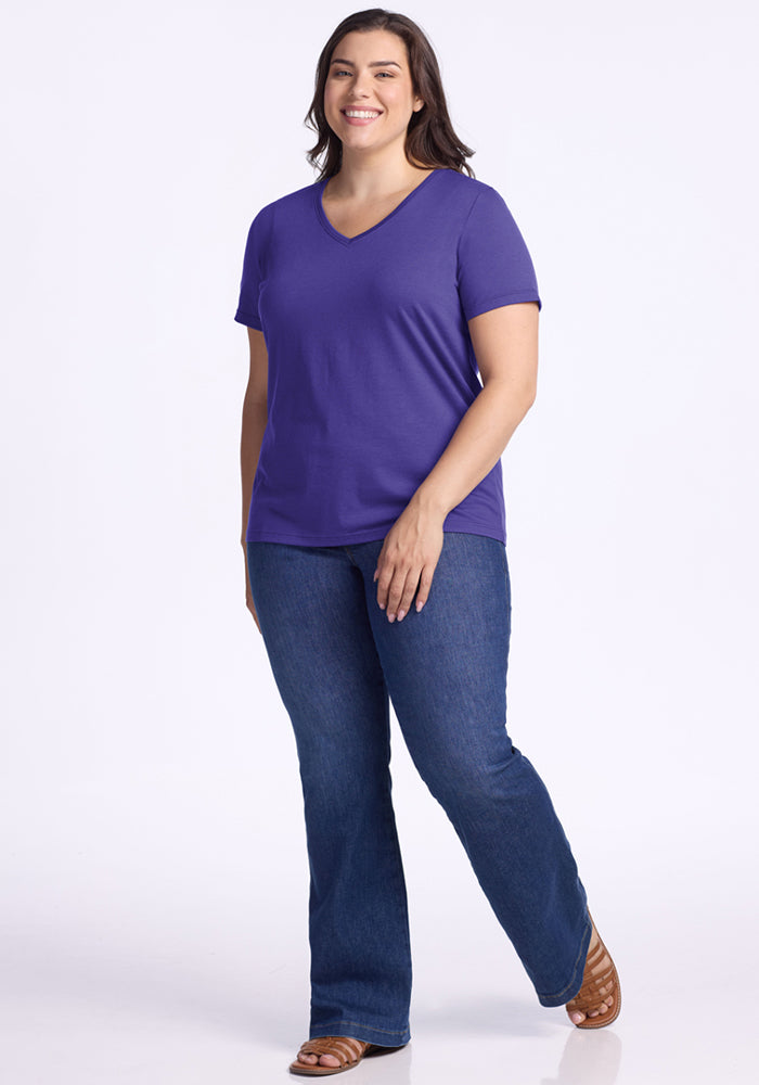 Smiling woman in Woolx Junie V Neck - Berry Indigo stands against a plain white background.