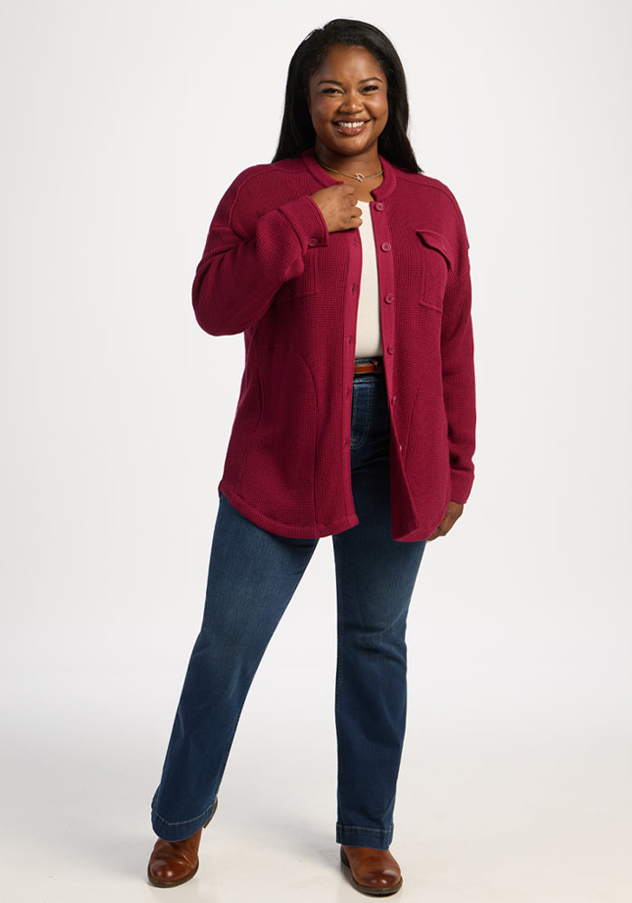 Woman wears Woolx Oaklynn Waffle Shacket in beet red, blue jeans, and brown shoes; hand near collar on white background.
