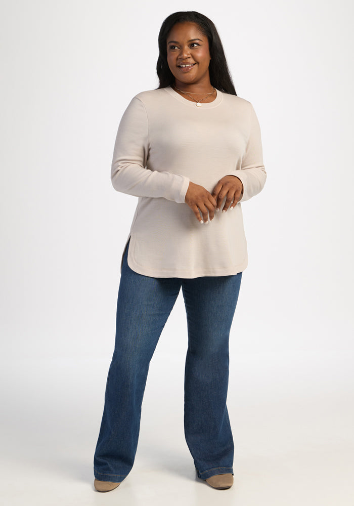 Woman in the Woolx Blair Tunic - Ecru and blue jeans smiles against a plain white background.