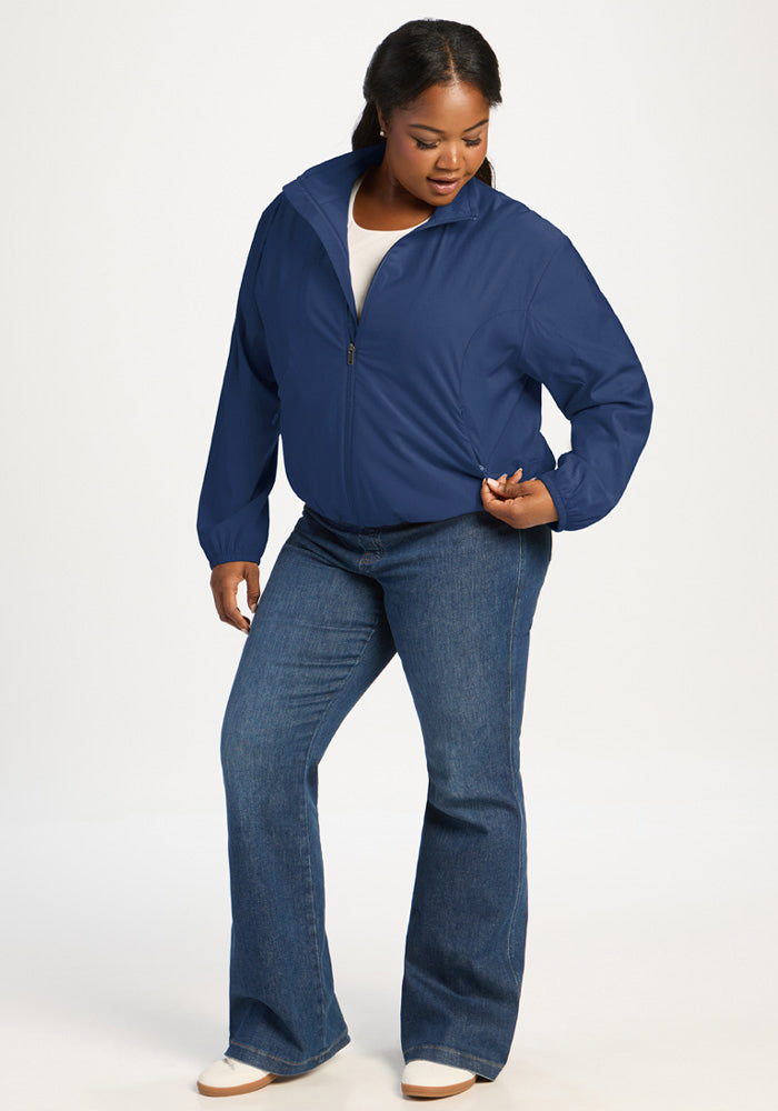 A woman wearing a dark blue Woolx Cooper Windbreaker - Vintage Indigo and blue flared jeans.