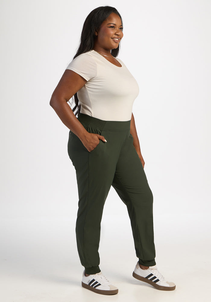 Woman smiles, hands in pockets, wearing Woolx Palmer Joggers - Duffel Bag and a beige t-shirt with sneakers.