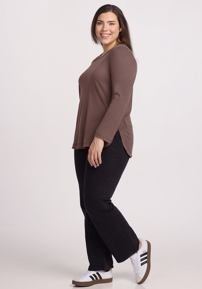 Woman smiles in the Woolx Hazel Tunic - Peppercorn, black jeans, and white sneakers against a plain background.