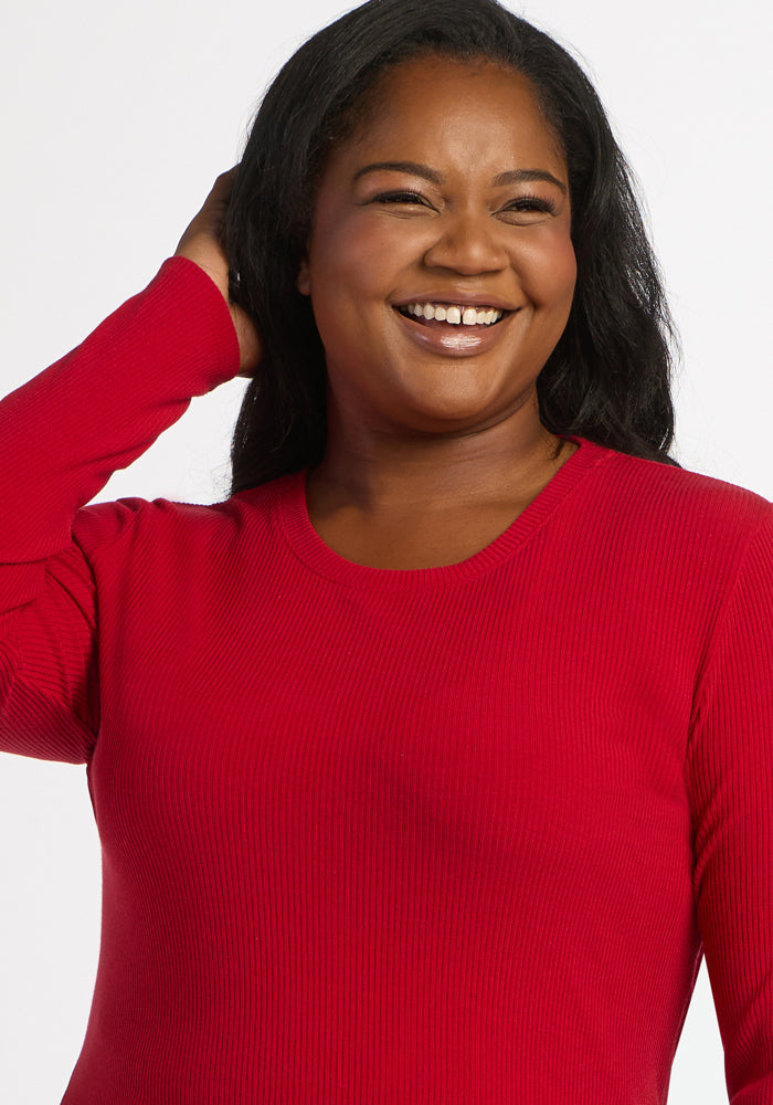 Woman smiles in a Woolx Hadley Ribbed Crew - Maraschino Cherry, touching her hair against a white backdrop.