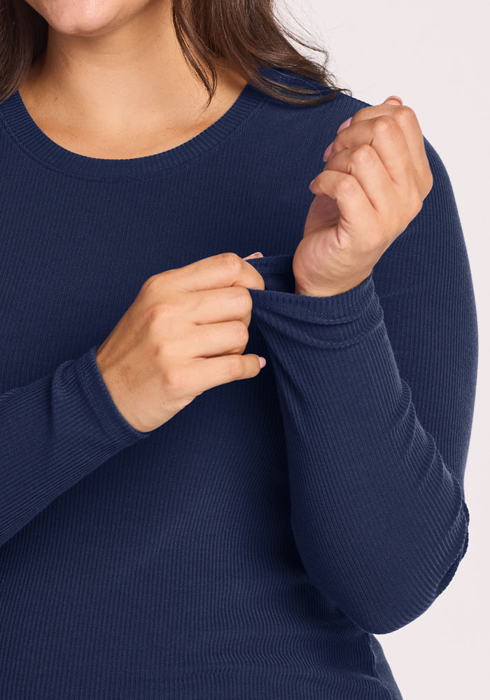 Woman in a Woolx Hadley Ribbed Crew - Ocean Cavern pulls a thumb hole open at the cuff with her left hand.